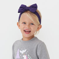 Child wearing a Deep Amethyst luxe bow headband and coordinating crewneck sweater