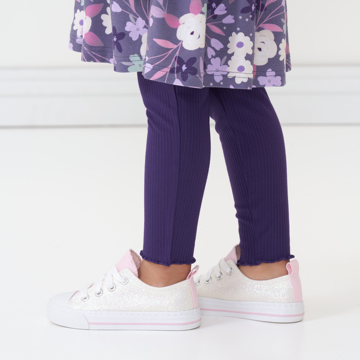 Close up image of a child wearing Deep Amethyst ribbed lettuce leggings and coordinating Sugar Plum Floral dress