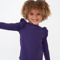 Close up image of a child wearing a Deep Amethyst ribbed flutter lettuce tee