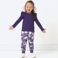 Child with her hands out to the side wearing a Deep Amethyst ribbed flutter lettuce tee and coordinating Sugar Plum Floral joggers