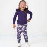 Child with a hand on her hip wearing a Deep Amethyst ribbed flutter lettuce tee and coordinating Sugar Plum Floral joggers