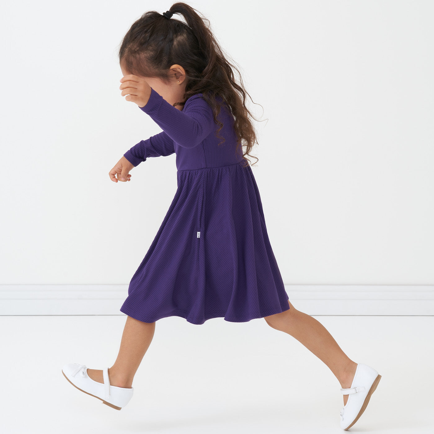 Side view image of a child running wearing a Deep Amethyst ribbed twirl dress