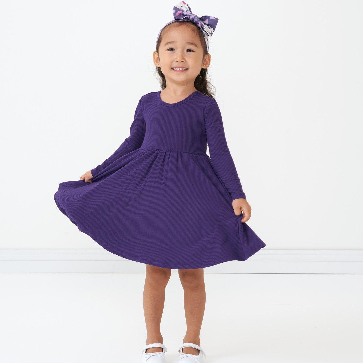 Child wearing a Deep Amethyst ribbed twirl dress and coordinating Sugar Plum Floral luxe bow headband