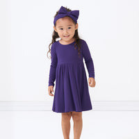 Child wearing a Deep Amethyst ribbed twirl dress and matching luxe bow headband