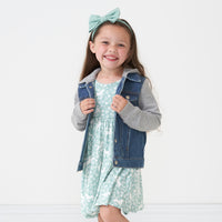 Child wearing a Midwash Blue denim jacket over a Unicorn Garden twirl dress with a matching luxe bow headband