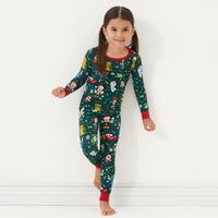 Child leaning against a wall wearing a Disney Christmas Party two piece pajama set