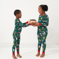 Two children holding a present wearing matching Disney Christmas Party pajamas