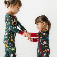 Two children holding hands wearing matching Disney Christmas Party pajamas