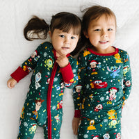Two children laying on a bed wearing matching Disney Christmas Party pajamas