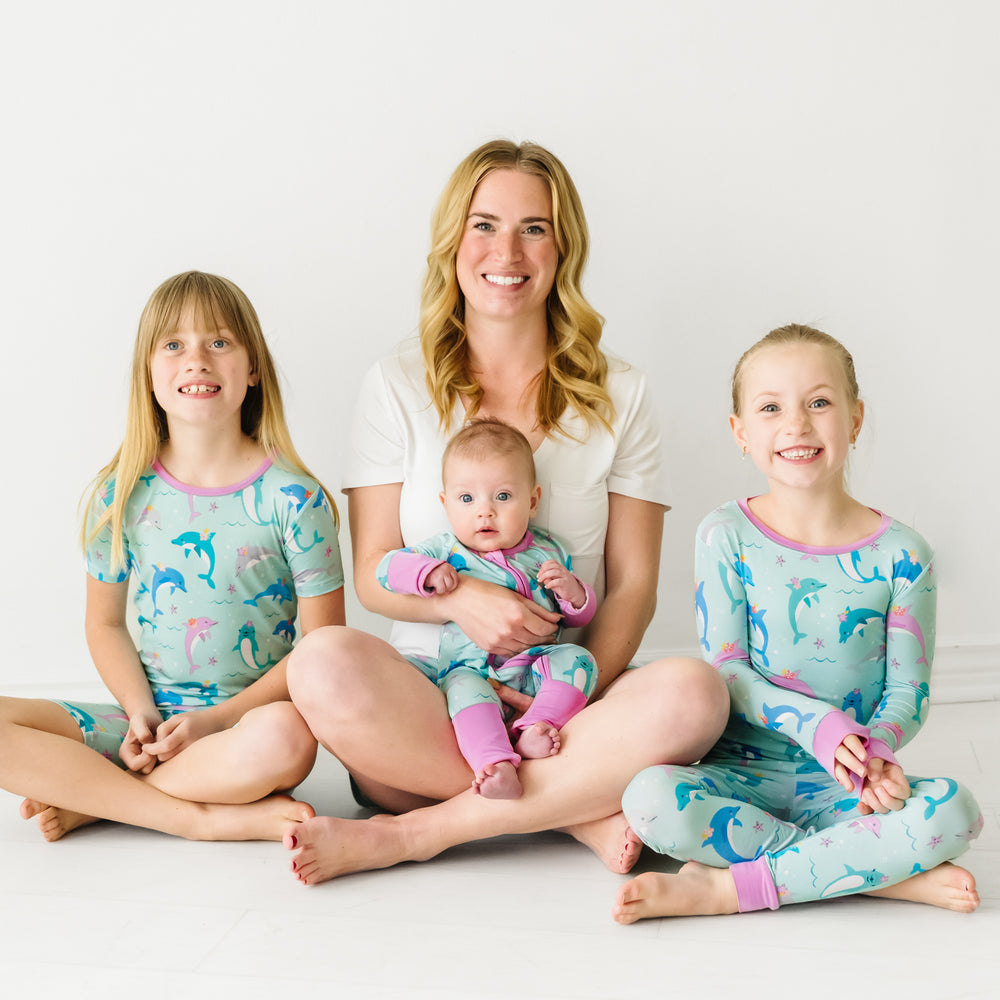 Family of four sitting on the ground wearing matching Dolphin Dance pajamas
