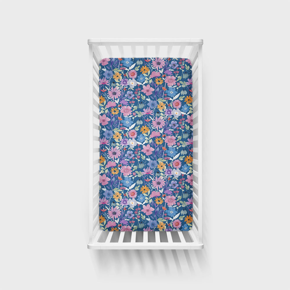 Top view of Dusk Blooms Fitted Crib sheet in a white crib