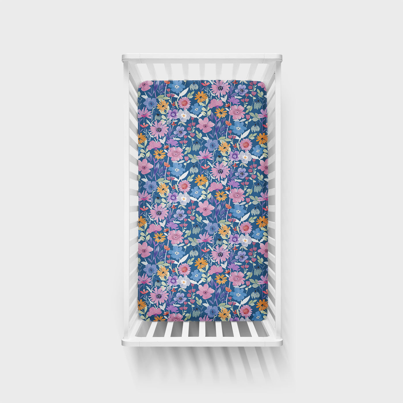 Top view of Dusk Blooms Fitted Crib sheet in a white crib