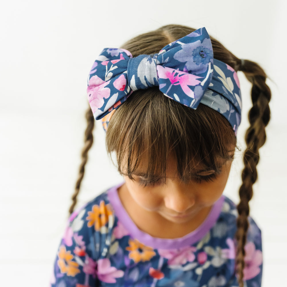 Close up image of a child wearing Dusk Blooms luxe bow headband with a matching Dusk Blooms two piece pajama set