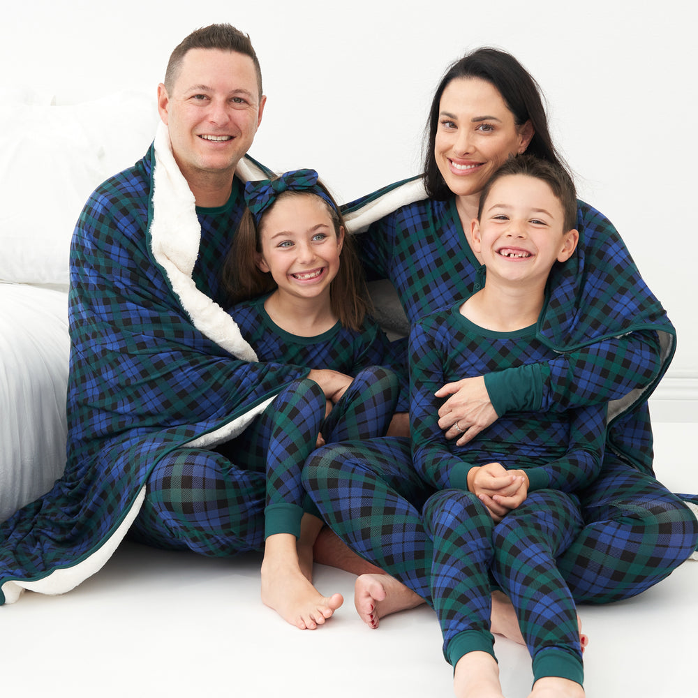 Family of four sitting on the ground with an Emerald Plaid plush oversized cloud blanket wrapped around them