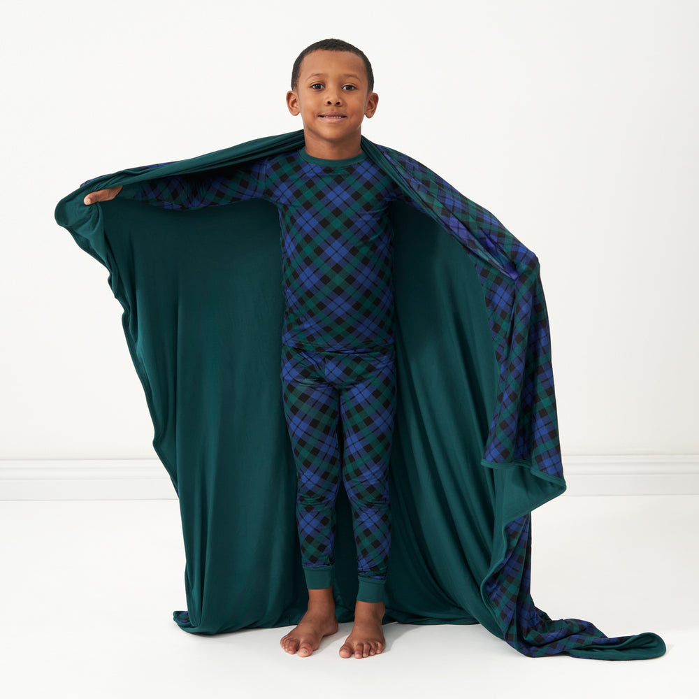 Child with an Emerald Plaid large cloud blanket around their shoulders showing the solid green backing