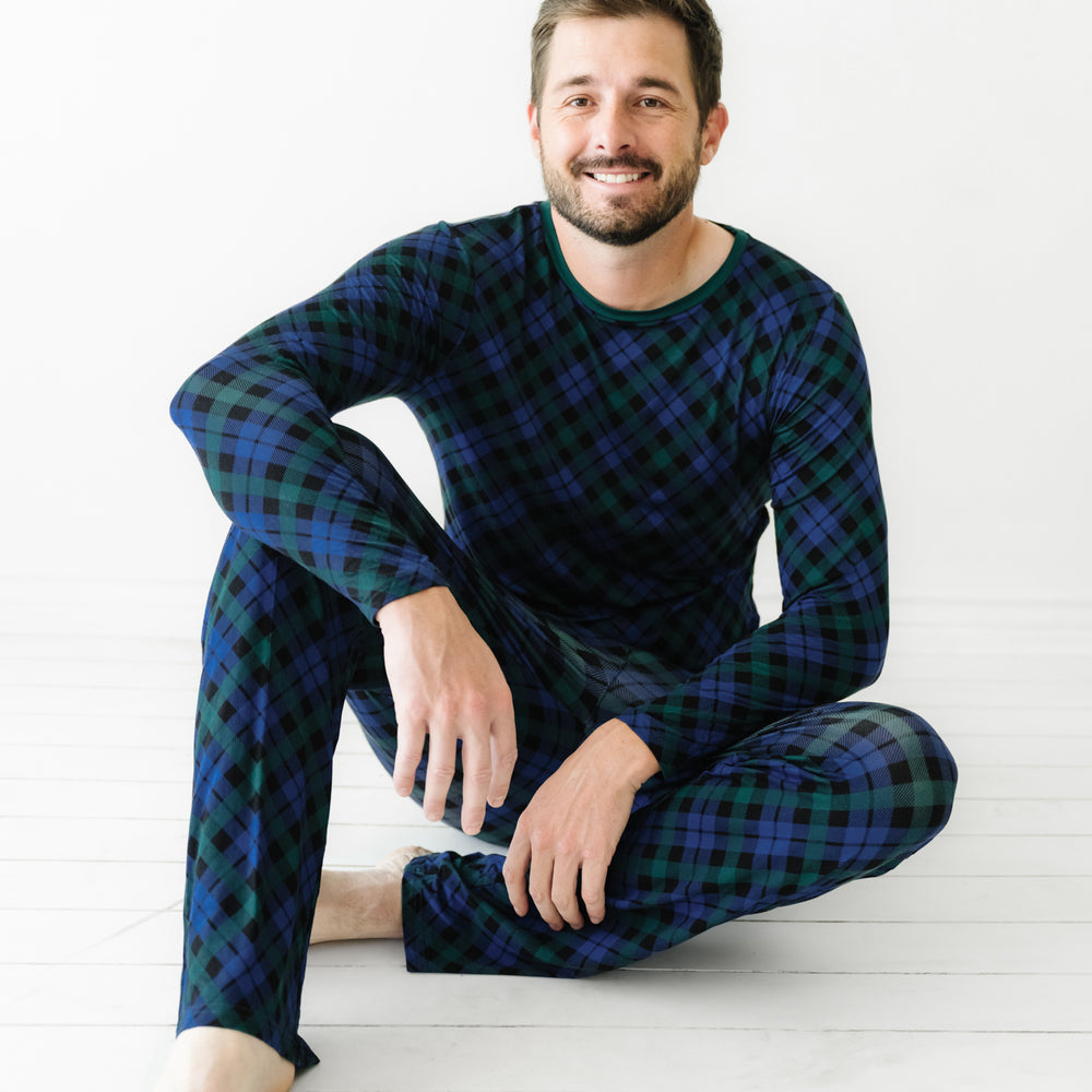 Man sitting on the ground wearing an Emerald Plaid men's pajama top and matching pants