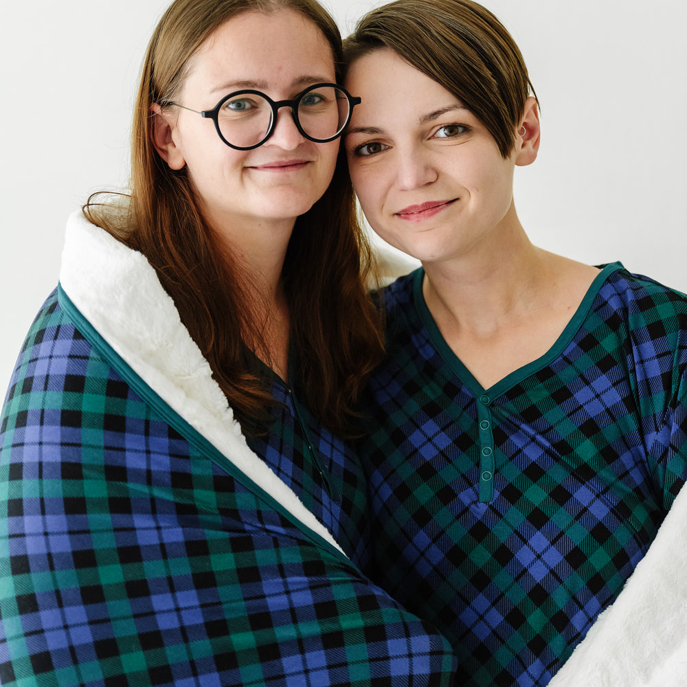 two women wearing matching Emerald Plaid women's pajama tops wrapped in a matching Emerald Plaid oversized cloud blanket