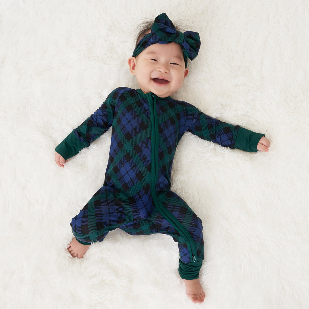 Child laying on a blanket wearing an Emerald Plaid luxe bow headband and matching zippy