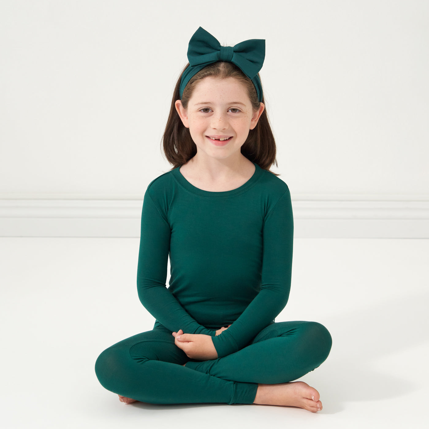 Child wearing an Emerald luxe bow headband and matching pajamas