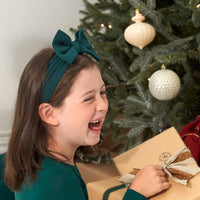 Child laughing wearing an Emerald luxe bow headband and matching pajamas