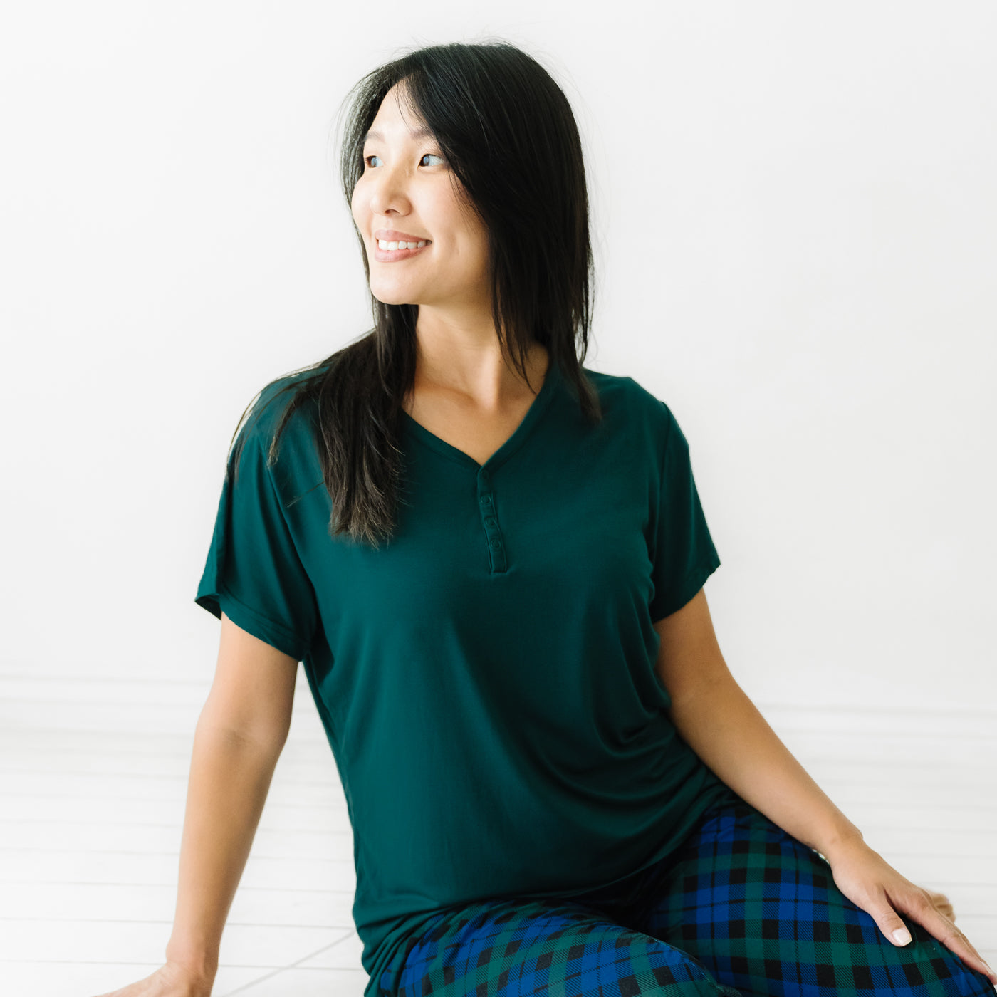 Woman sitting on the ground wearing an Emerald women's short sleeve pajama top and coordinating pajama pants