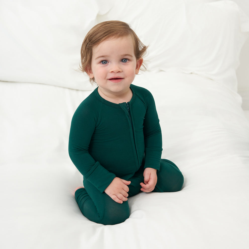 Child kneeling on a bed wearing an Emerald zippy
