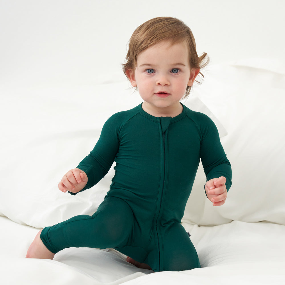 Close up image of a child kneeling on a bed wearing an Emerald zippy