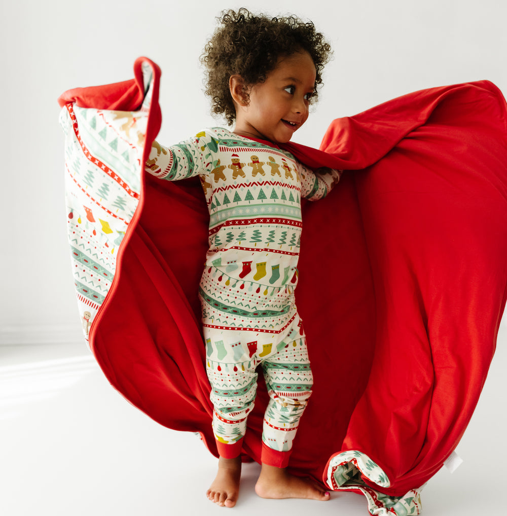 Child holding a Fair Isle large cloud blanket showing the solid red backing