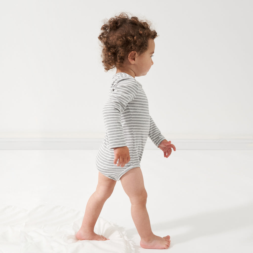 Click to see full screen - profile view of a child walking wearing a Heather Gray and Ivory Stripe bodysuit