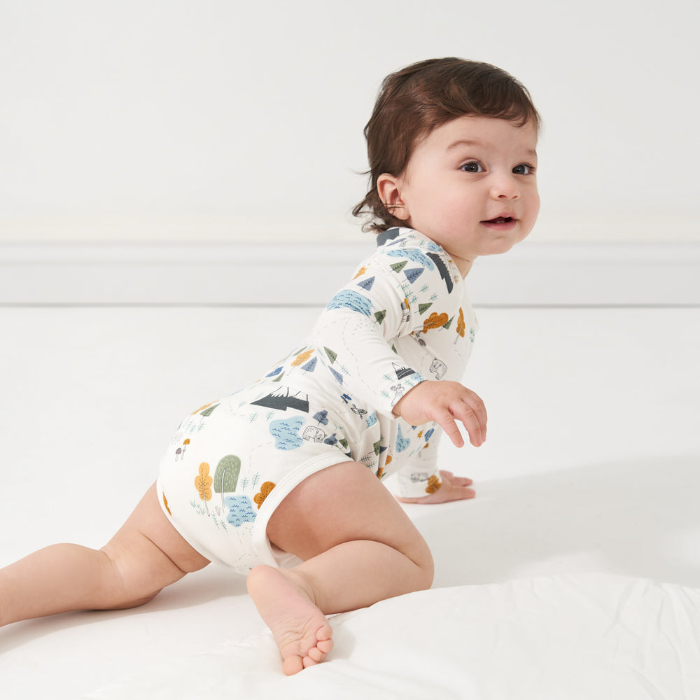 Click to see full screen - Child crawling on the floor wearing a Let's Explore printed bodysuit