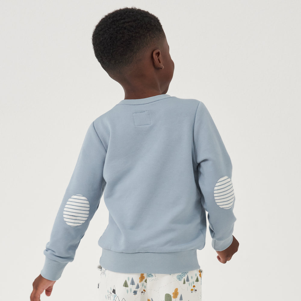 Click to see full screen - Back view of a child wearing a Fog elbow patch crewneck showing the elbow patches