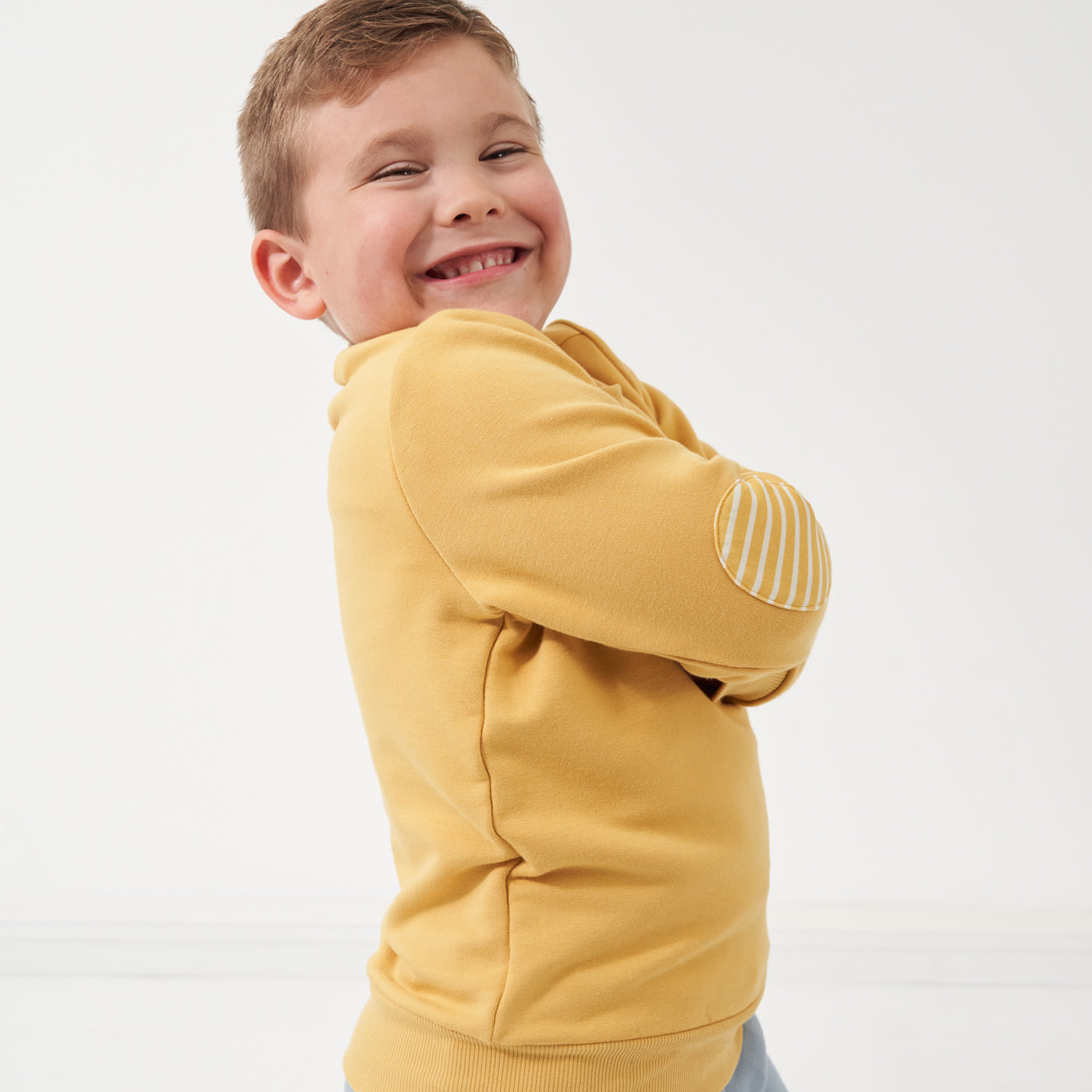 Child wearing a Honey elbow patch crewneck showing the elbow patch