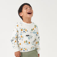 Child laughing wearing a Let's Explore printed crewneck sweatshirt