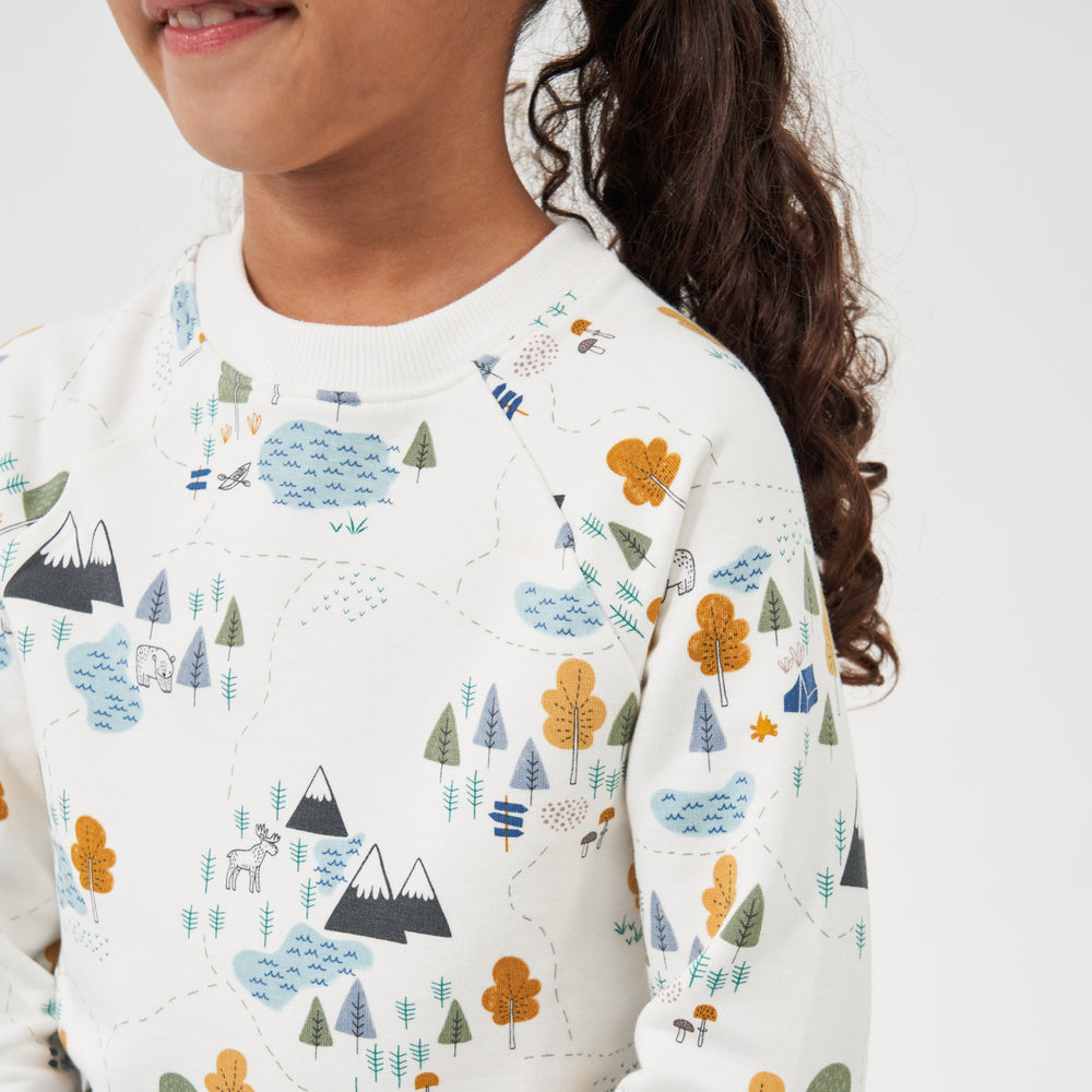 Close up image of a child wearing a Let's Explore printed crewneck sweatshirt