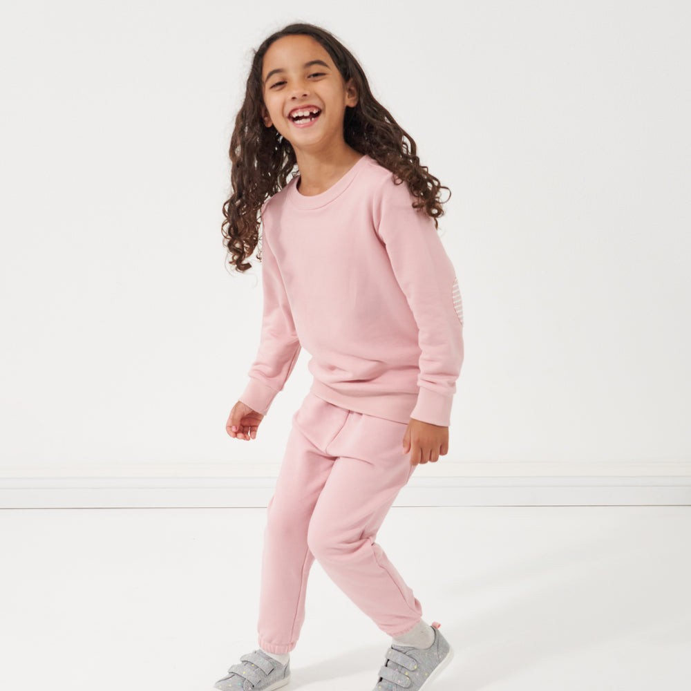 Child playing wearing a Mauve Blush crewneck paired with matching Mauve Blush paperbag joggers