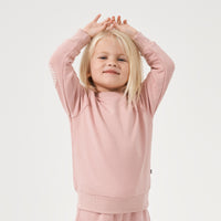 Child posing with her hands over her head wearing a Mauve Blush crewneck