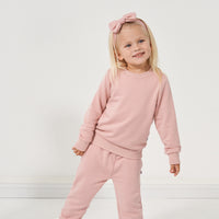 Child wearing a Mauve Blush crewneck paired with Mauve Blush paperbag joggers and a matching luxe bow headband