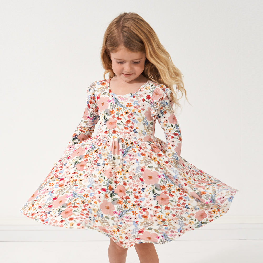 Child twirling with her hands in her pockets wearing a Mauve Meadow printed twirl dress