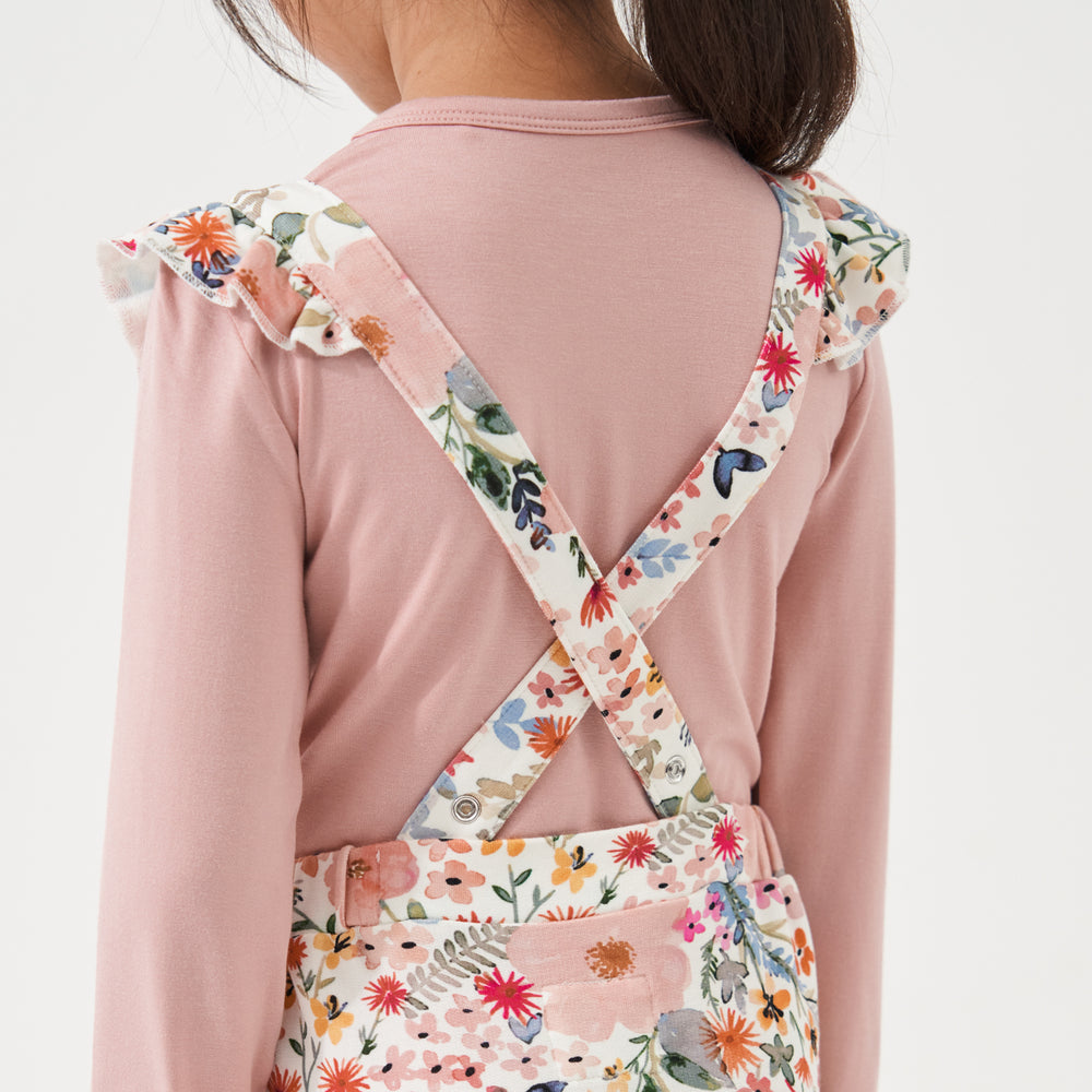 Click to see full screen - Close up image of the back of a child wearing Mauve Meadow printed ruffle overalls over a Mauve classic tee