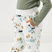 Close up image of a child with their hands in their pockets wearing Let's Explore printed joggers