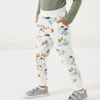 Child standing with their hands in their pockets wearing Let's Explore printed joggers