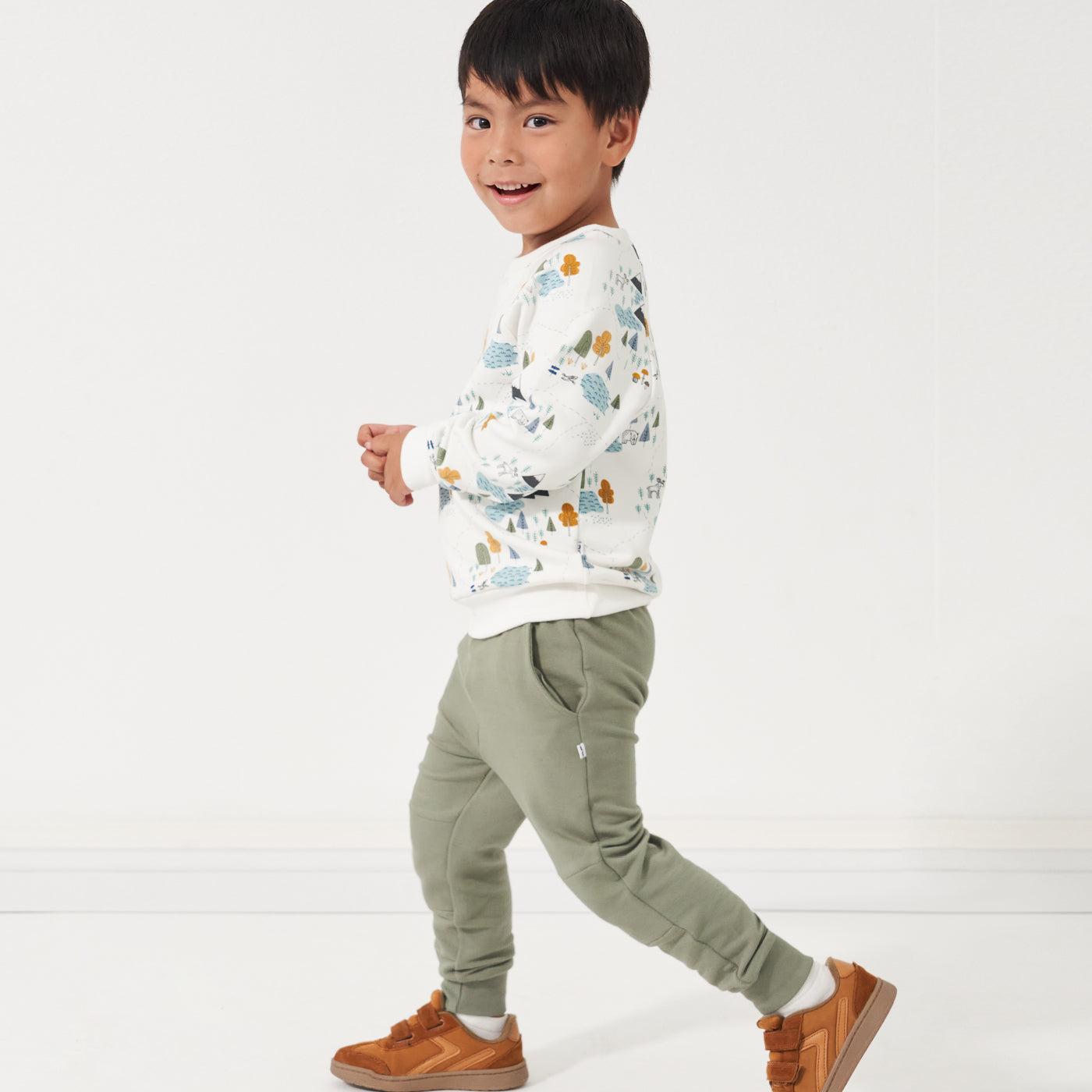 Side view image of a child wearing Moss joggers and a coordinating Let's Explore crewneck sweatshirt