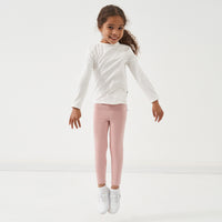 Child jumping wearing Mauve Blush leggings paired with an Ivory classic tee