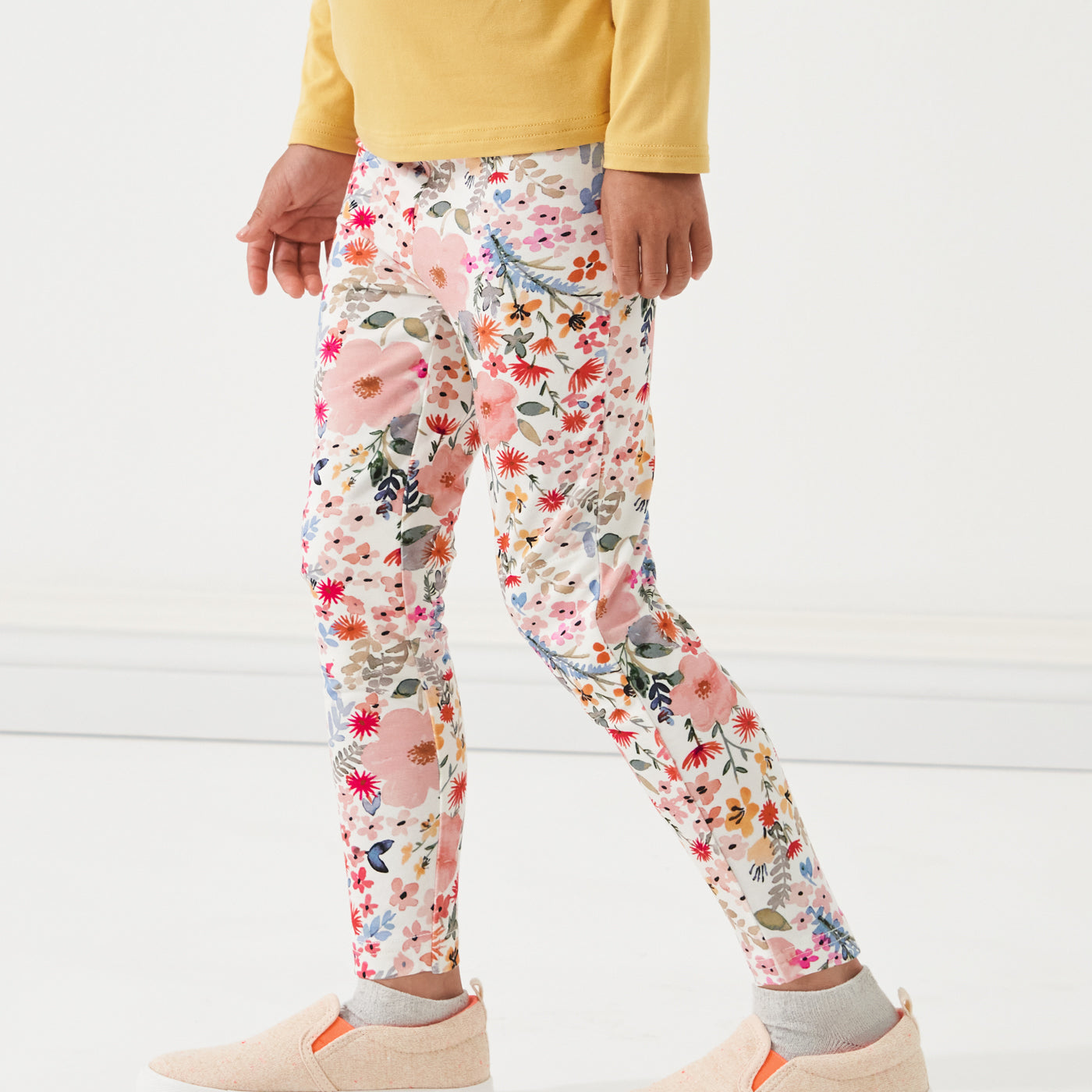 close up profile image of a child wearing Mauve Meadow printed leggings paired with a Honey Crewneck