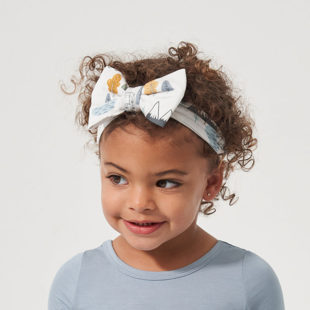Close up image of a child wearing a Let's Explore printed luxe bow headband