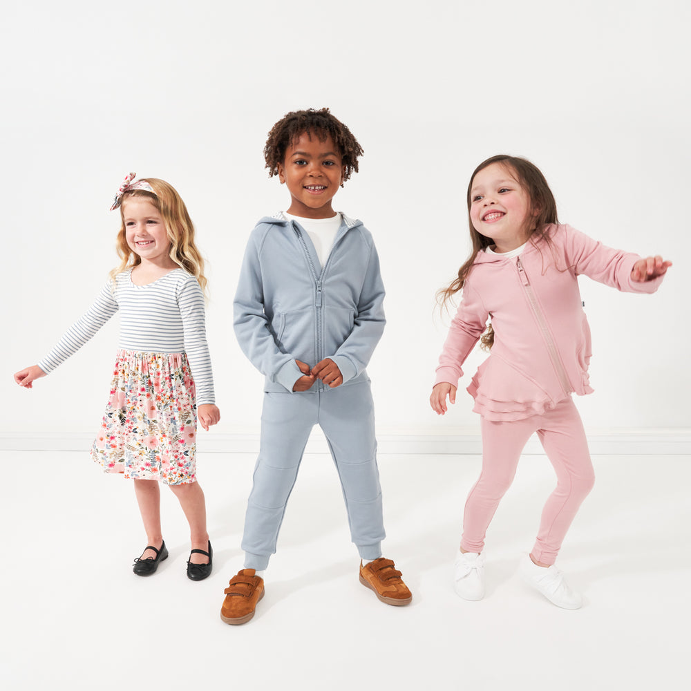 Three children wearing coordinating Play by Little Sleepies outfits in Fog, Mauve Blush, and Mauve Meadow