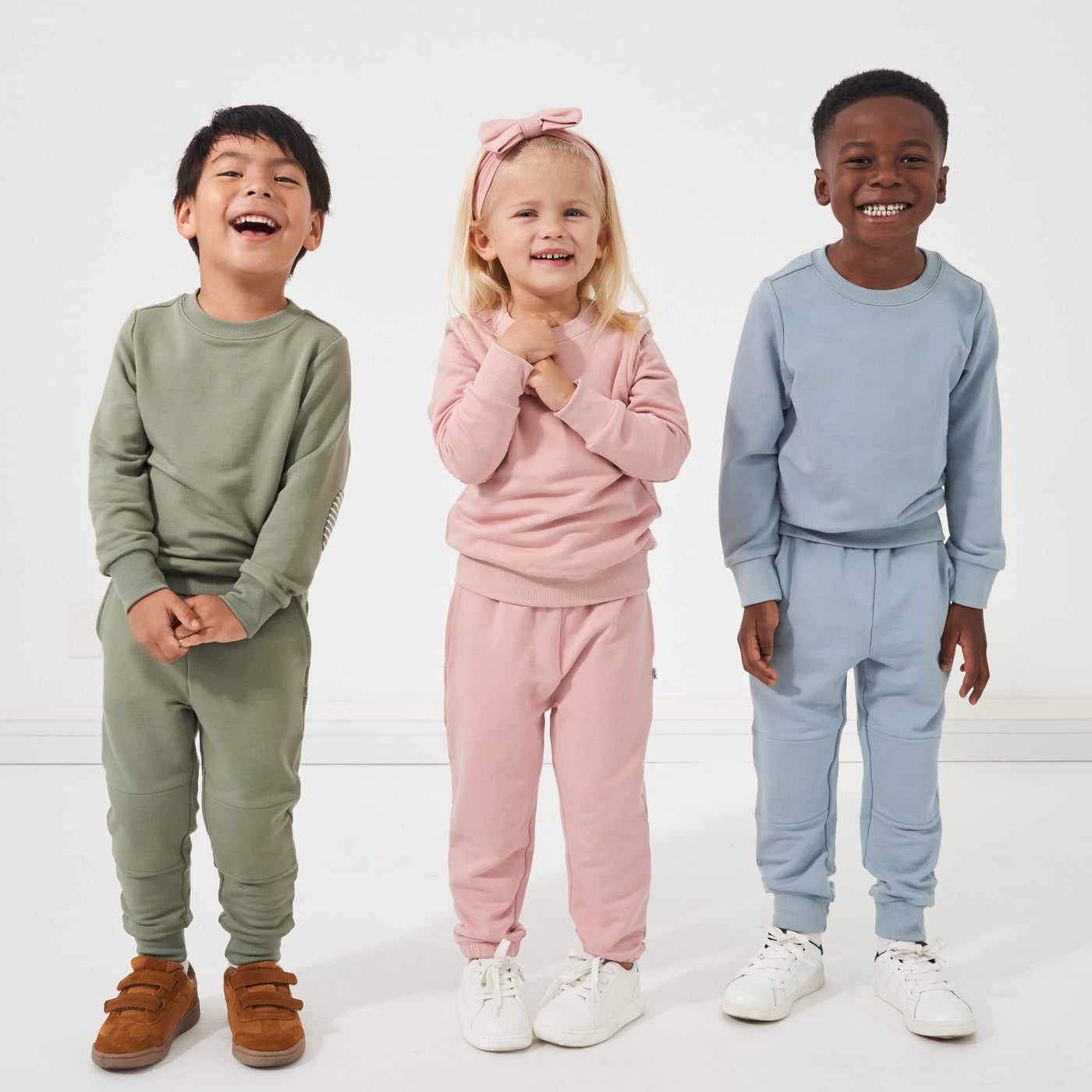 Three children wearing Play by Little Sleepies elbow patch crewnecks and joggers