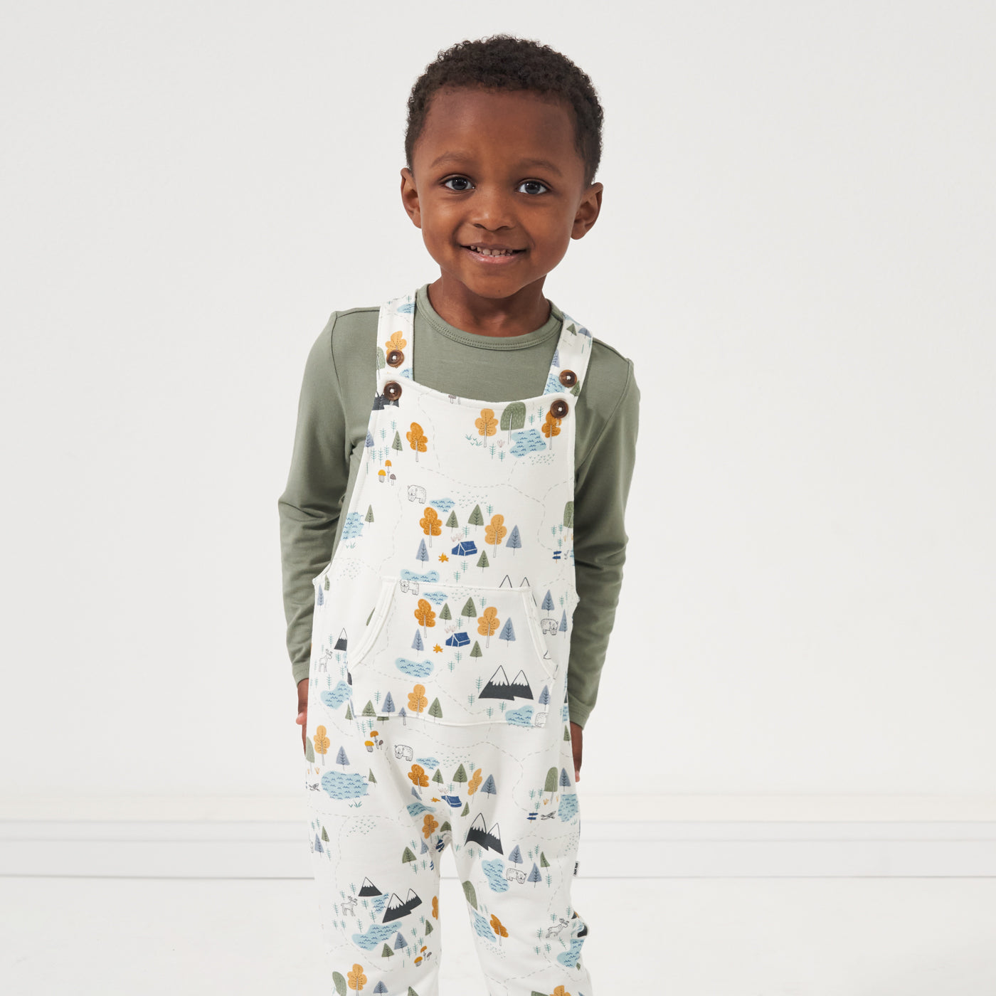 Child wearing a Moss classic tee and coordinating Let's Explore printed overall