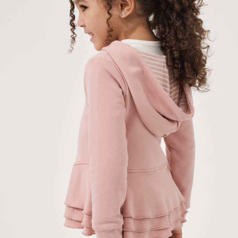 Click to see full screen - Close up profile view of a child wearing a Mauve Blush peplum hoodie