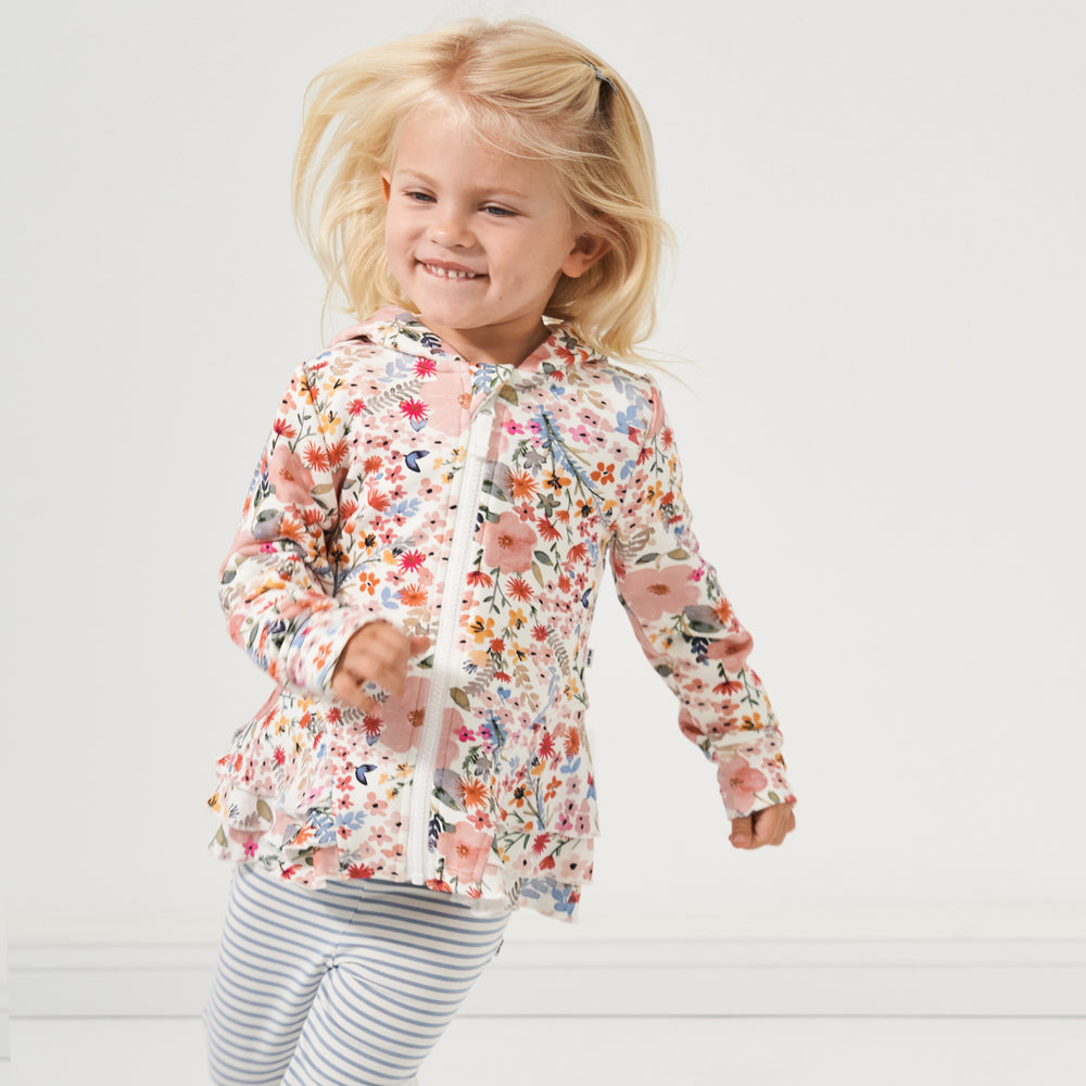 Child playing wearing a Mauve Meadow printed peplum hoodie paired with Ivory and Fog striped leggings